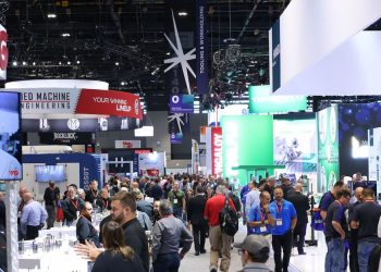 Crowded exhibit hall floor at IMTS with attendees walking between vendor booths and overhead signage