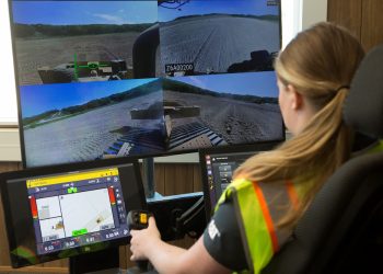 Worker monitoring Cat GRADE autonomous dozer operation across multiple camera displays