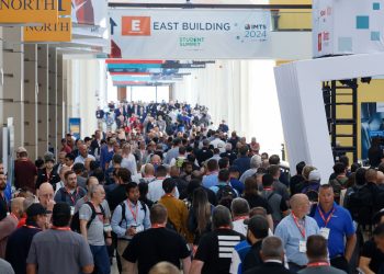 Crowd of badged attendees walking beneath an IMTS 2024 East Building banner at McCormick Place in Chicago