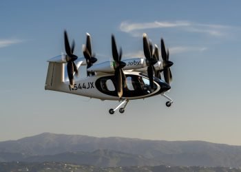 Joby Aviation electric air taxi in flight with landing gear extended and six tilt-rotors, tail number N544JX