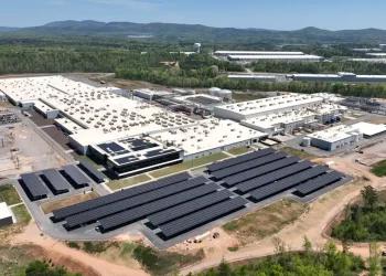 Aerial view of the Qcells solar manufacturing campus in Cartersville, Georgia with rows of solar arrays in the foreground