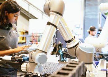 Manufacturing technician using a teach pendant to program a collaborative robot arm